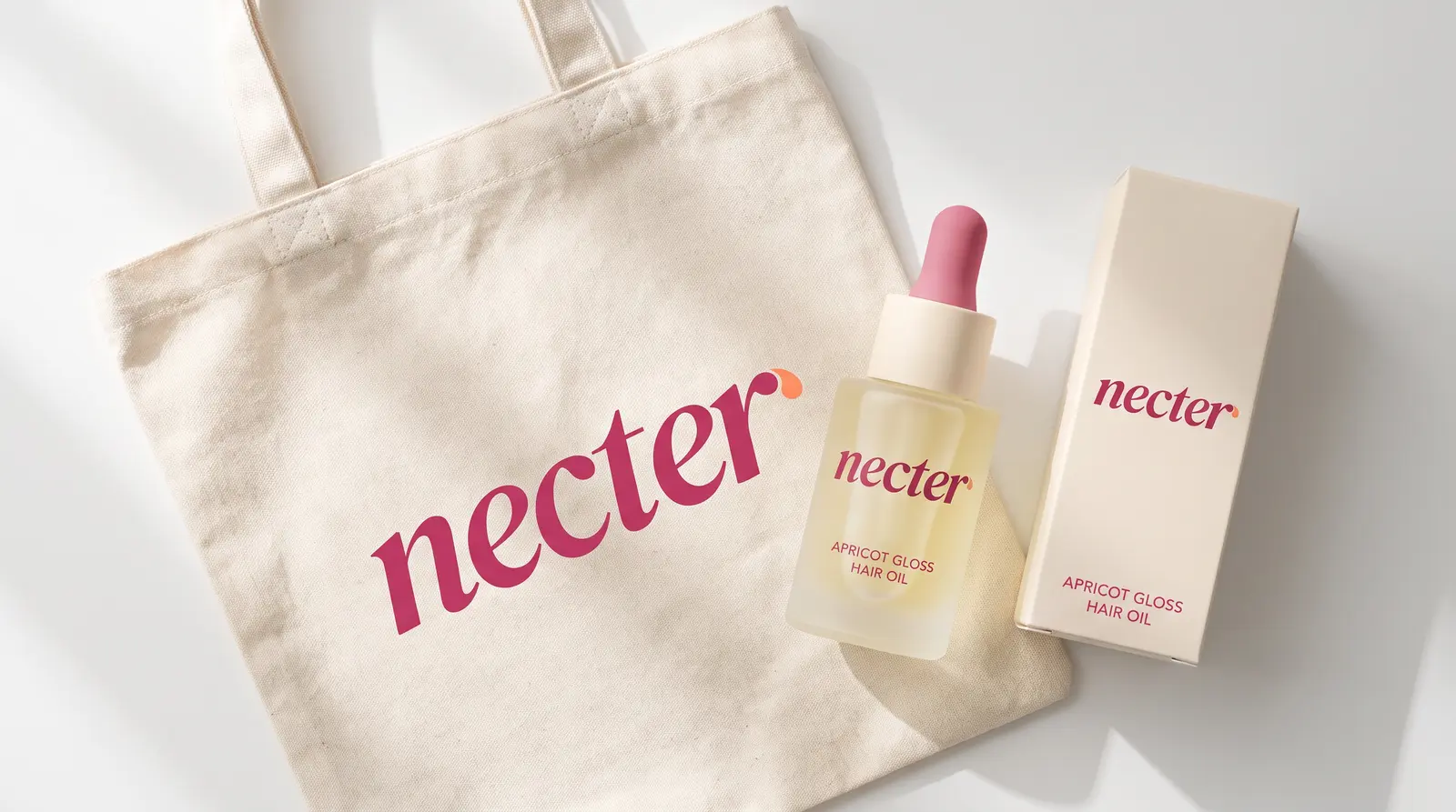 A cream canvas tote printed with the raspberry necter logo, beside the bottle and carton