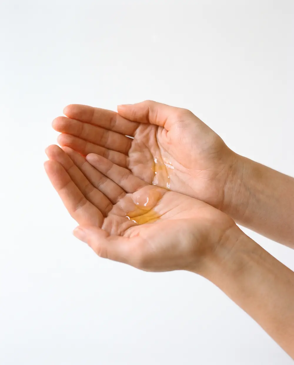 Cupped palms holding a few golden drops of oil