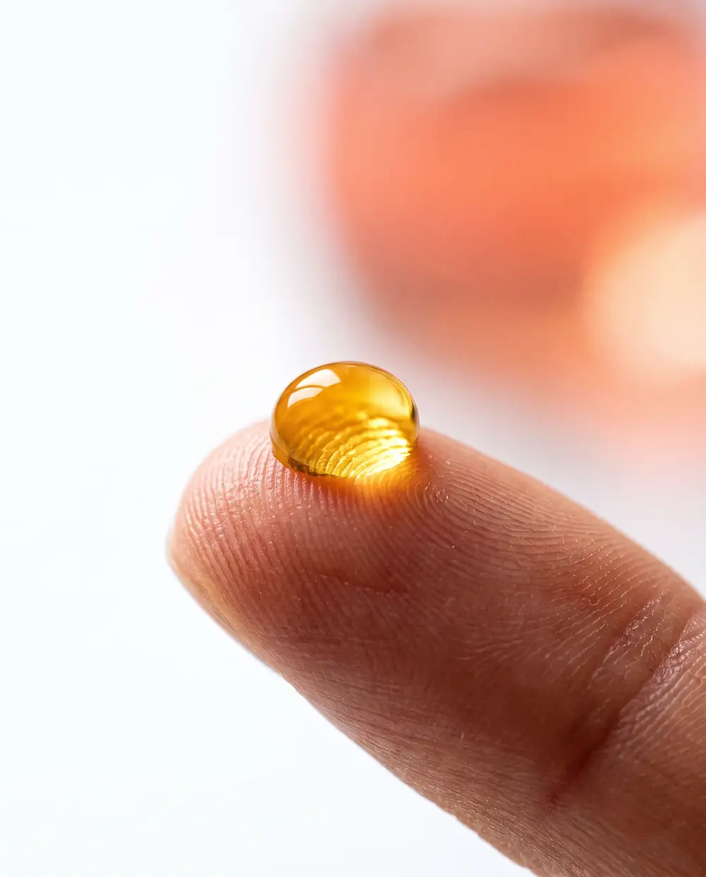 A single golden drop of oil on a fingertip